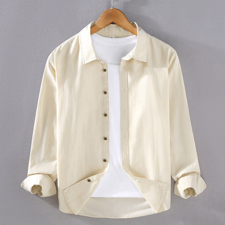 Camicia beige da uomo su gruccia, maniche lunghe, abbinata a t-shirt bianca. Moda casual, abbigliamento maschile elegante, sfondo grigio.