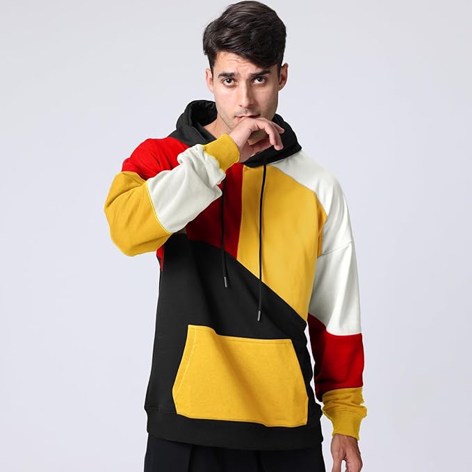 Uomo con felpa multicolore a blocchi di colore rosso, giallo, nero e bianco, cappuccio e tasca frontale. Moda casual, abbigliamento streetwear.