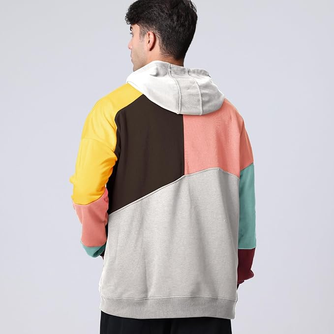 Uomo con felpa multicolore a blocchi, cappuccio e maniche lunghe. Moda casual, abbigliamento streetwear, tendenze autunno-inverno.