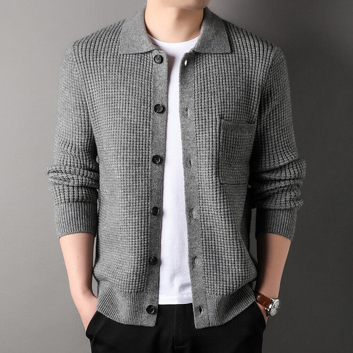 Cardigan grigio a maglia grossa con bottoni, indossato su maglietta bianca. Moda uomo, abbigliamento casual elegante, stile autunnale.