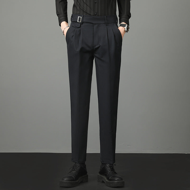 Pantaloni eleganti neri da uomo, con cintura e pieghe, abbinati a camicia scura e scarpe nere. Moda maschile formale, abbigliamento classico.