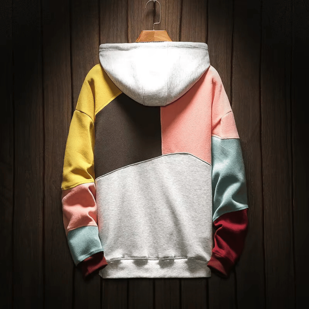 Felpa con cappuccio multicolore, design a blocchi, sfondo in legno. Moda casual, abbigliamento streetwear, tendenze autunno-inverno.