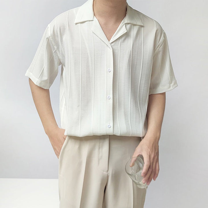 Camicia bianca a righe verticali, maniche corte, indossata da uomo con pantaloni beige. Moda estiva elegante, stile casual chic.
