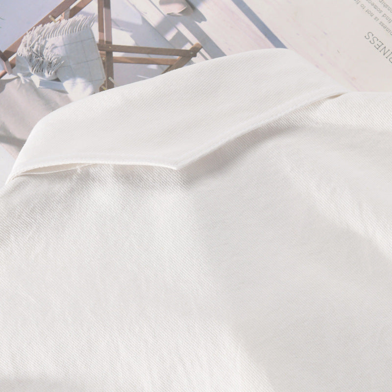 Camicia bianca in cotone su sfondo di riviste, tessuto morbido e leggero, moda elegante, abbigliamento casual, stile minimalista.
