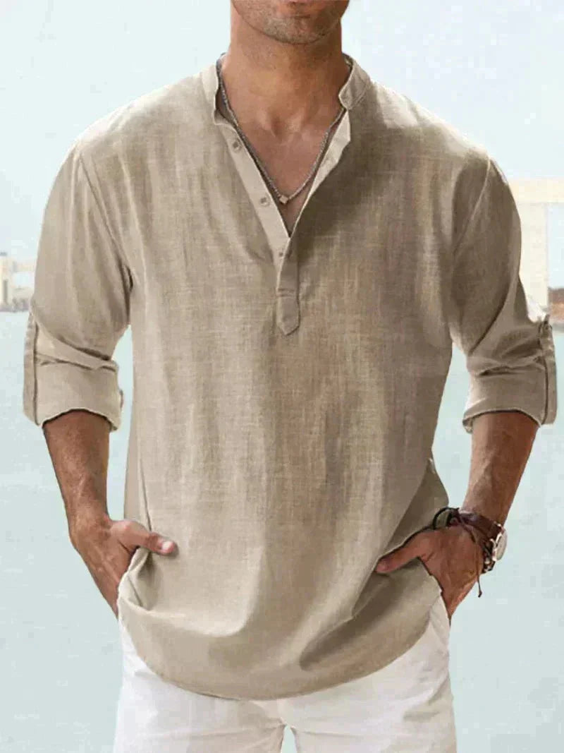 Uomo con camicia di lino beige a maniche lunghe, collo alla coreana, abbinata a pantaloni bianchi. Stile casual estivo maschile.