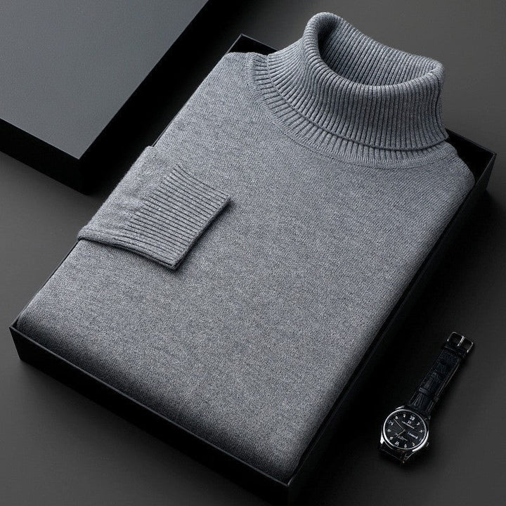 Maglione dolcevita grigio piegato in scatola nera, accanto a orologio da polso elegante. Moda uomo, abbigliamento invernale, stile classico.