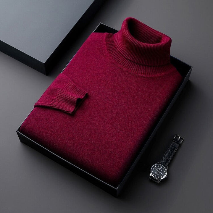 Maglione dolcevita rosso bordeaux in scatola regalo, elegante e caldo, accanto a orologio da polso nero. Moda uomo, abbigliamento invernale.