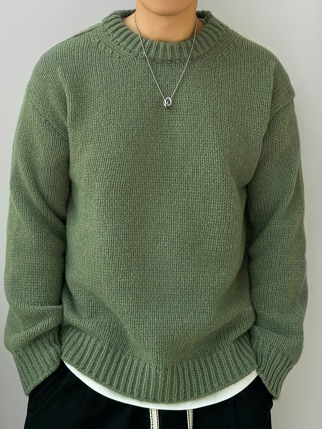 Maglione verde oliva in lana, indossato da una persona, con collana argento. Moda autunnale, abbigliamento casual, stile confortevole.