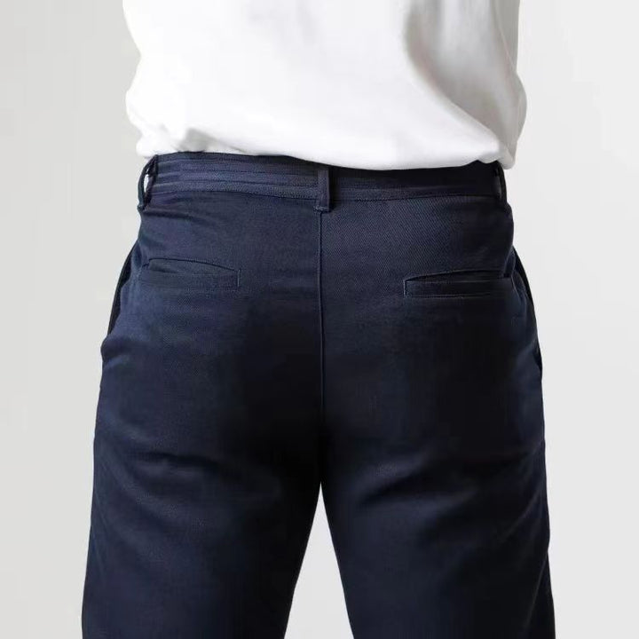 Pantaloni eleganti blu scuro da uomo, tasche posteriori, indossati con camicia bianca. Moda maschile, abbigliamento formale, stile classico.