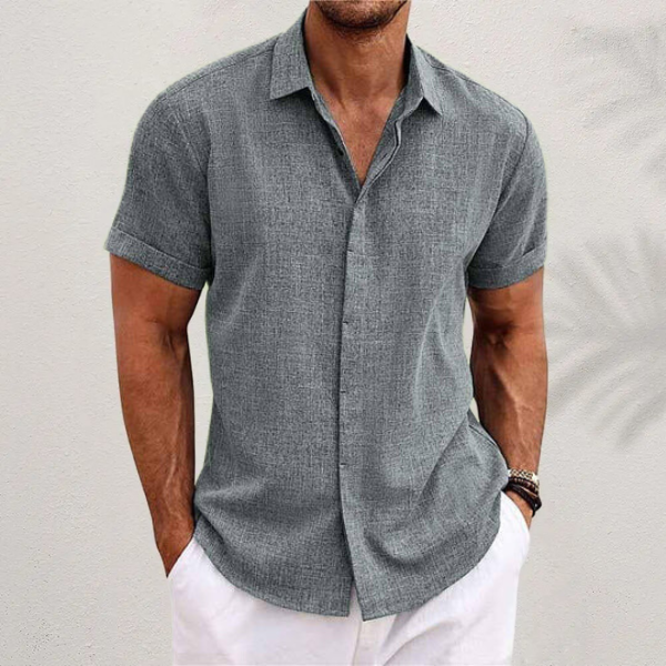 Camicia uomo estiva grigia a maniche corte, tessuto leggero, abbinata a pantaloni bianchi. Look casual elegante, moda maschile estiva.