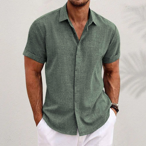 Camicia uomo verde lino, maniche corte, stile casual estivo, abbinata a pantaloni bianchi. Look fresco e moderno per la moda maschile estiva.