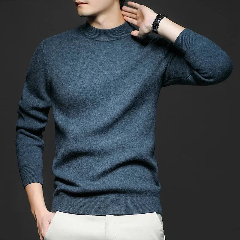 Maglione uomo blu scuro in cashmere, maniche lunghe, indossato da modello su sfondo grigio. Moda maschile elegante, abbigliamento invernale.