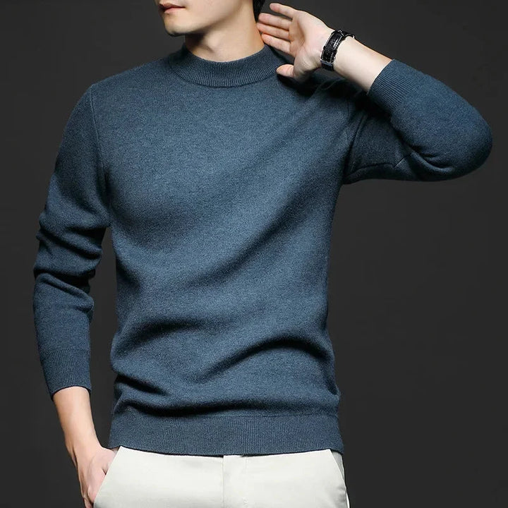 Maglione uomo blu scuro in cashmere, maniche lunghe, indossato da modello su sfondo grigio. Moda maschile elegante, abbigliamento invernale.
