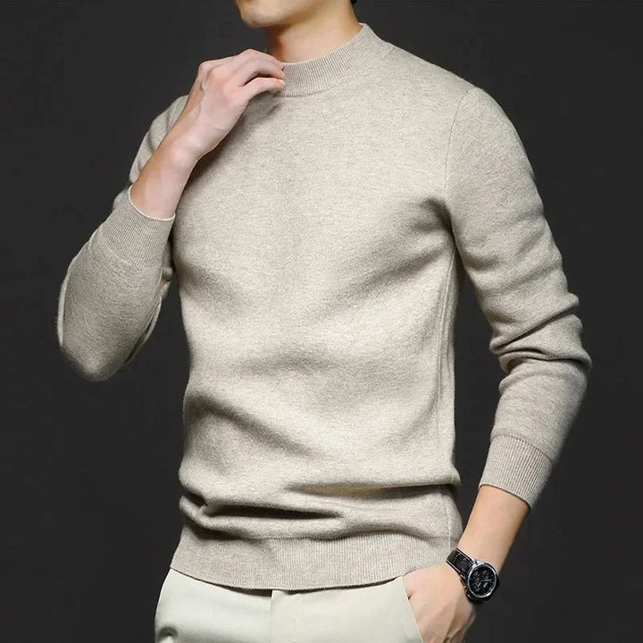 Maglione beige uomo elegante, maniche lunghe, indossato con pantaloni chiari. Moda maschile autunno inverno, stile casual chic.
