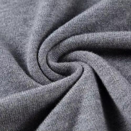 Tessuto grigio in lana morbida, primo piano con pieghe a spirale. Materiale caldo e accogliente, ideale per maglioni e abbigliamento invernale.