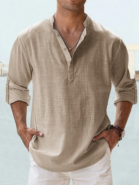 Camicia uomo lino beige, maniche lunghe arrotolate, stile casual estivo, colletto alla coreana, abbinata a pantaloni bianchi.