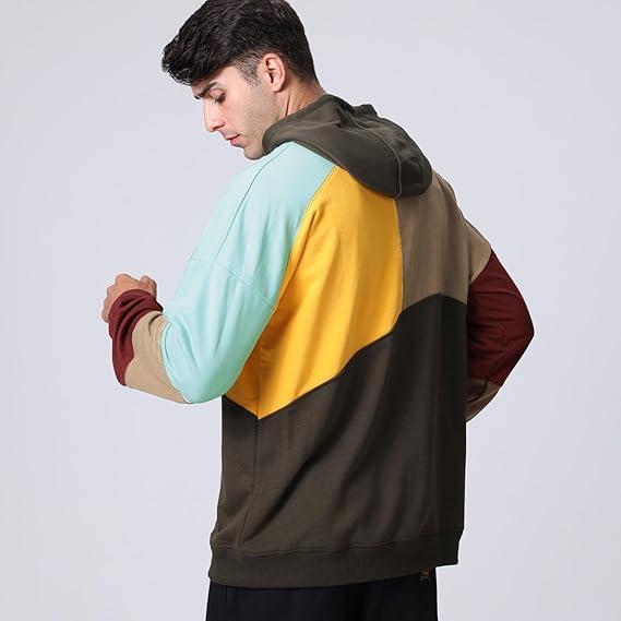 Uomo con felpa multicolore a blocchi, cappuccio, maniche lunghe, design moderno. Moda casual, abbigliamento autunnale, stile urbano.