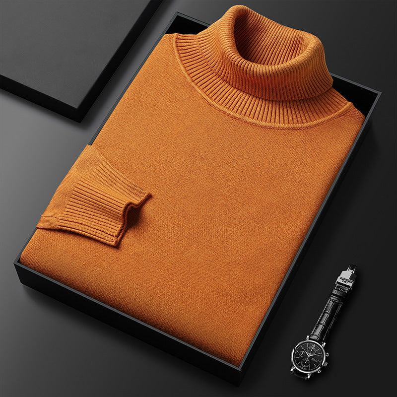 Maglione arancione a collo alto piegato in scatola nera su sfondo scuro, accanto a orologio da polso elegante. Moda uomo, abbigliamento invernale.