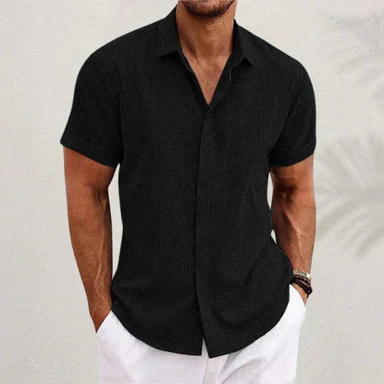 Camicia nera a maniche corte da uomo, stile casual estivo, abbinata a pantaloni bianchi. Look elegante e moderno per la moda maschile.